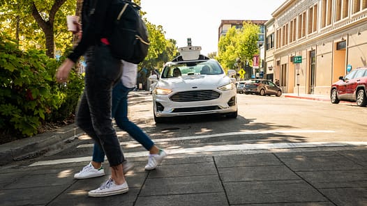 Ein autonomes Auto mit Radar-Aufbau fährt auf einen Fußgängerüberweg zu